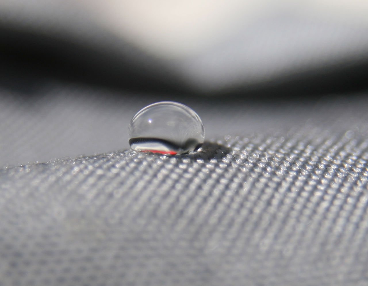 close up of a droplet of water on a gray mesh surface