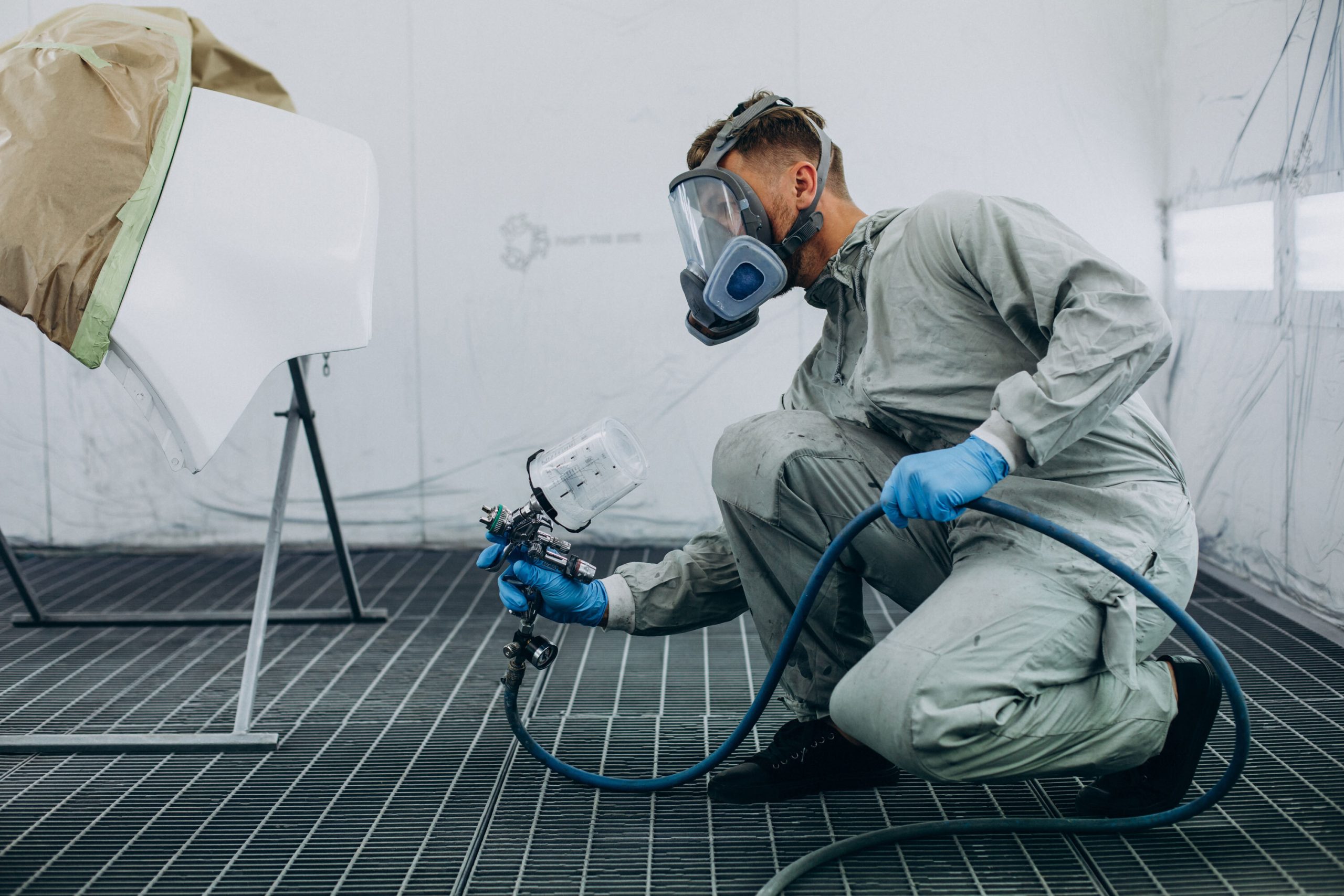 man using industrial paint machine to paint car door white