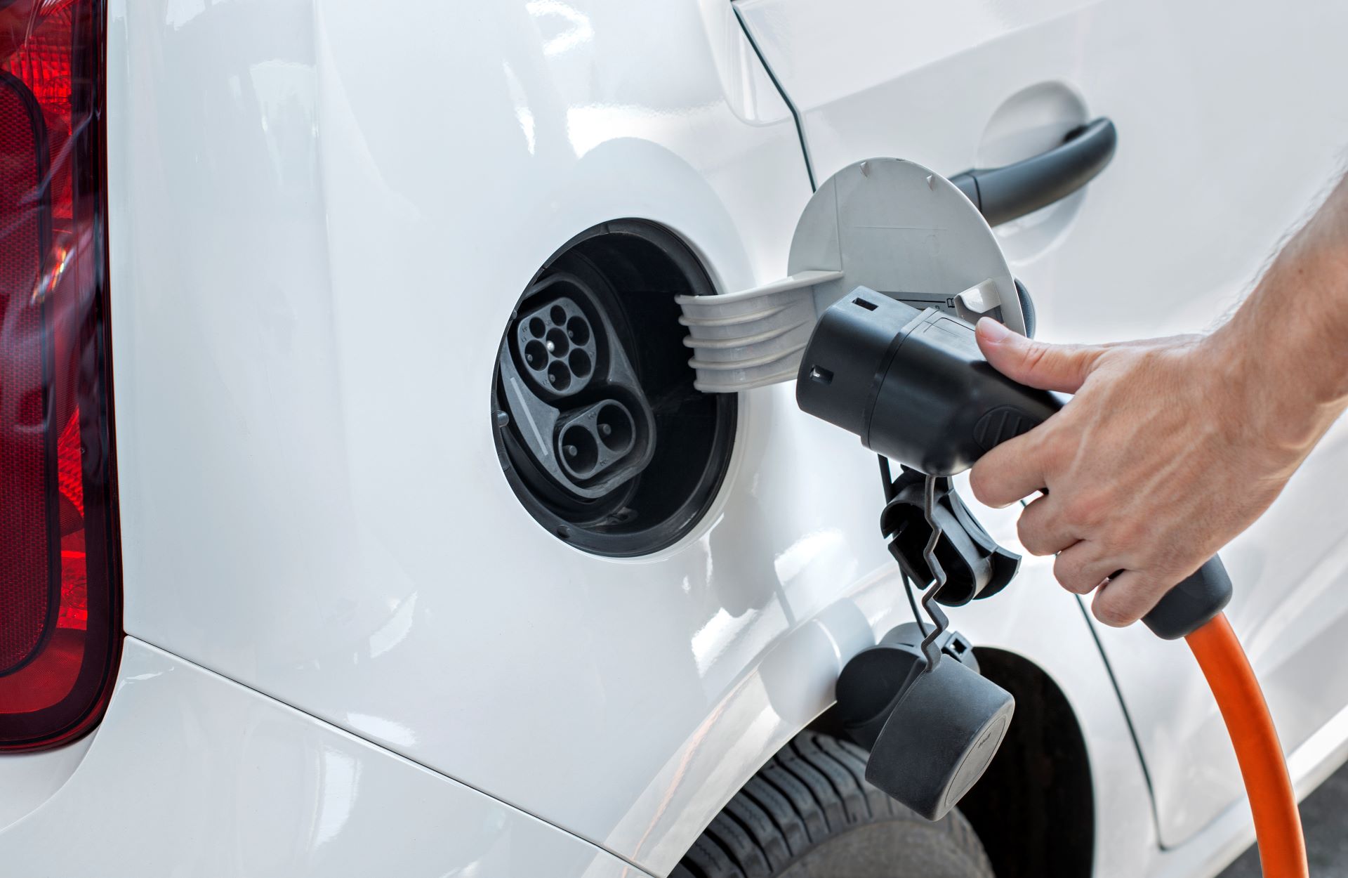 person plugging a charger into an electric vehicle