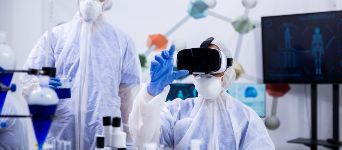 Scientist working with virtual reality goggles in research laboratory with her assistant in the background.