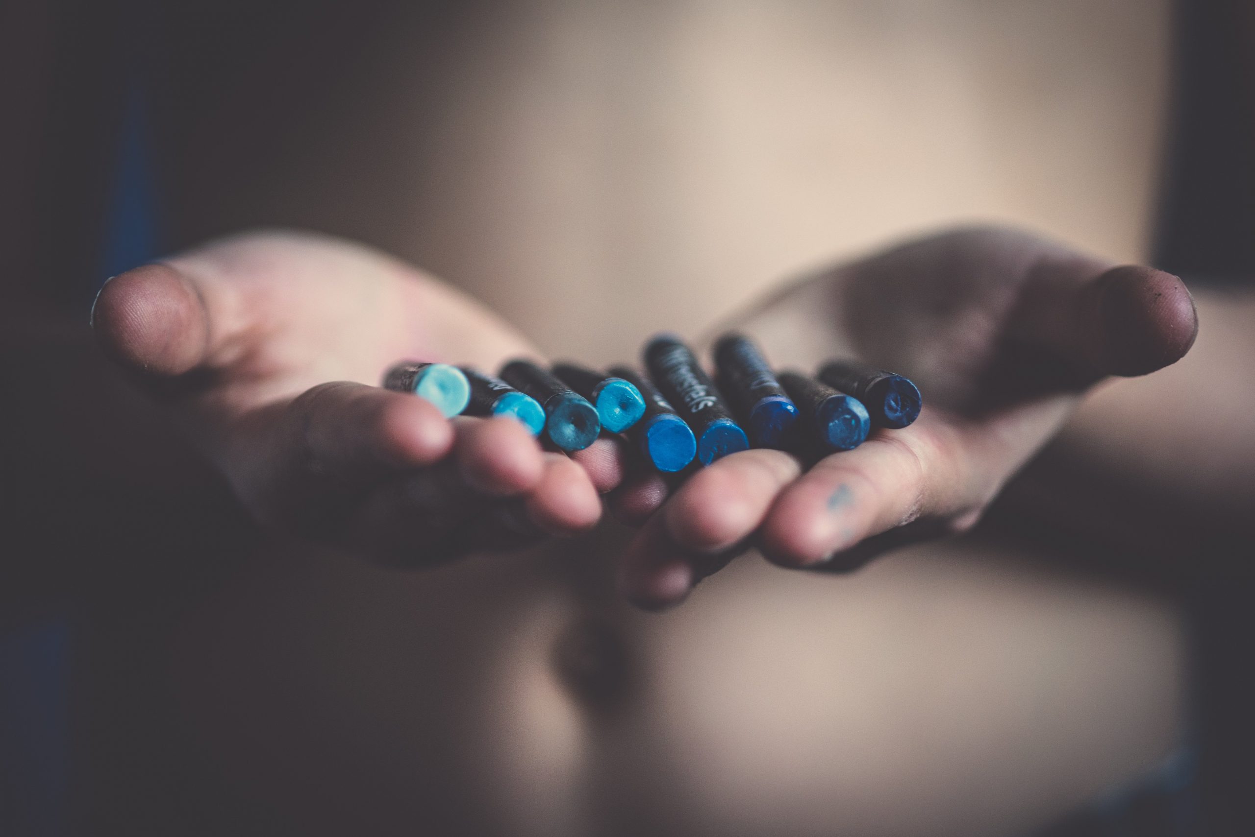 hands holding a variety of blue crayons